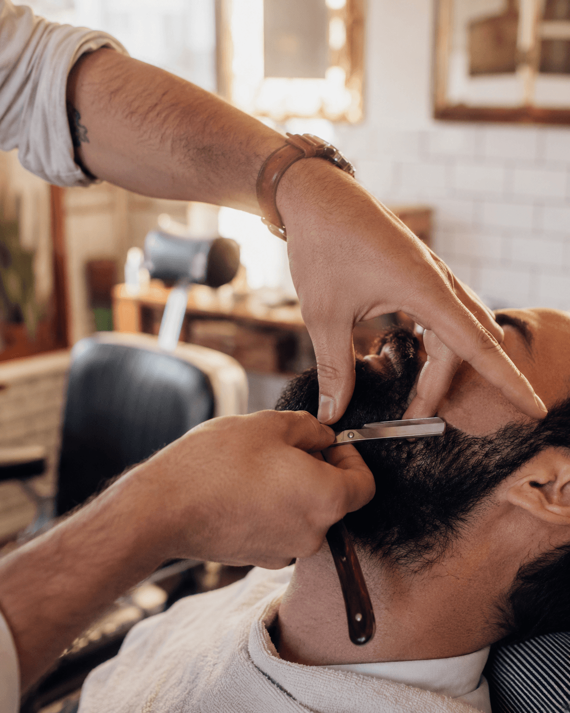 Barbier taillant une barbe au rasoir dans son shop
